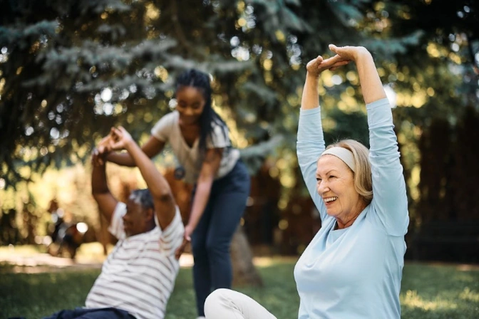 Older adults stretching outdoors with a fitness instructor